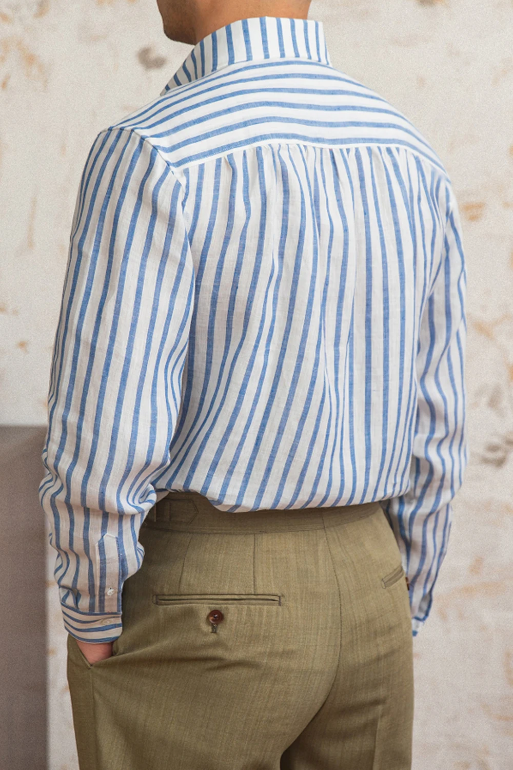 Back view of men's blue striped linen shirt showing pleated yoke