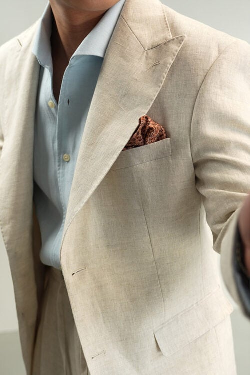 Close-up of men's natural beige linen blazer with peak lapel and pocket square