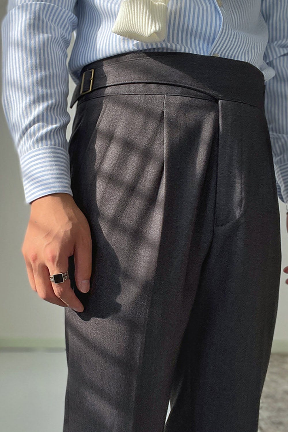 Close-up of charcoal grey trouser waistband and pleat detail