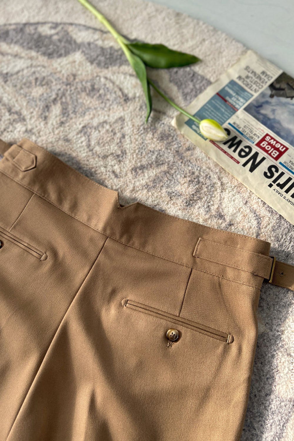 Close-up of black trouser buckle waist tab and pocket detail
