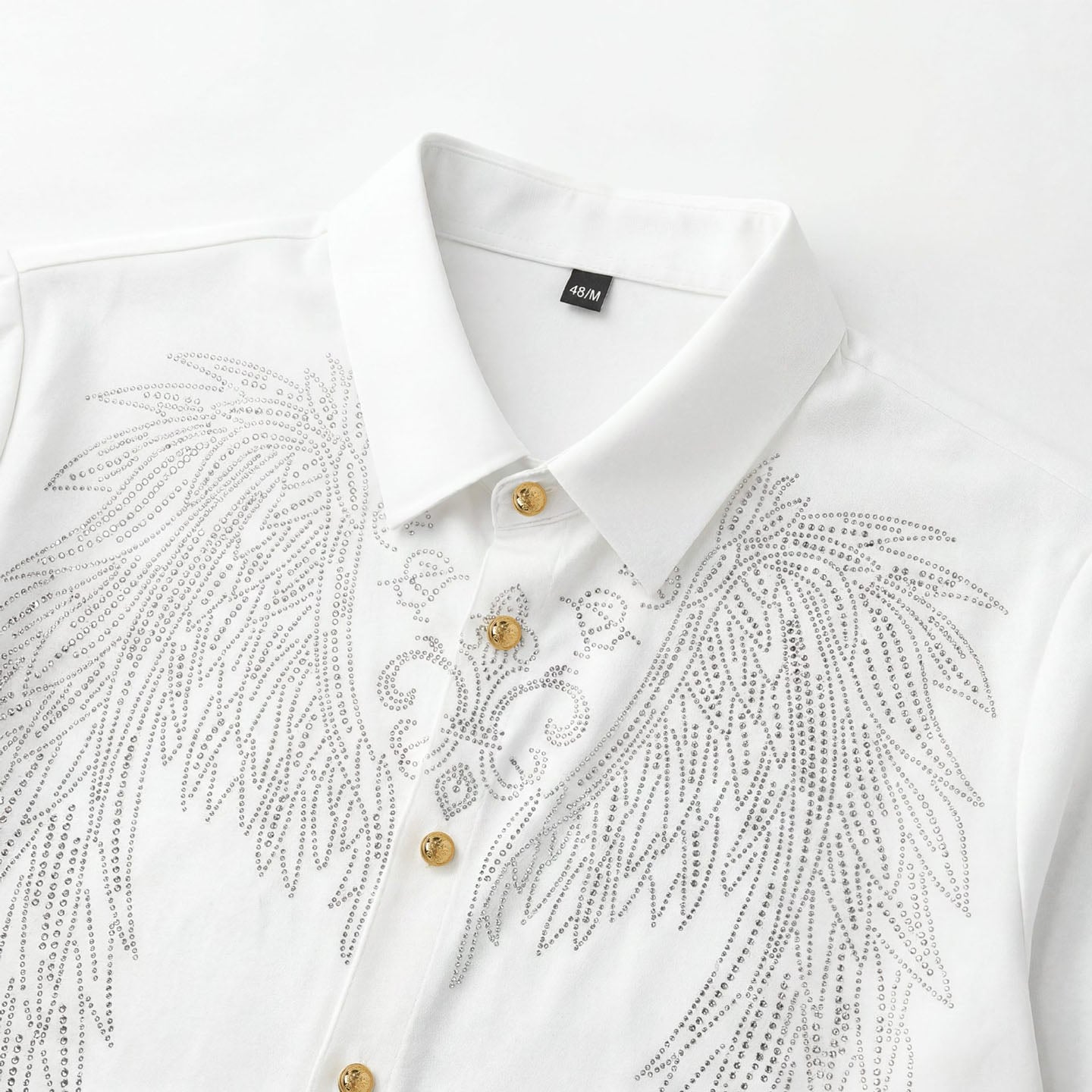 Close-up of white shirt with silver rhinestone angel wing design and gold-tone buttons