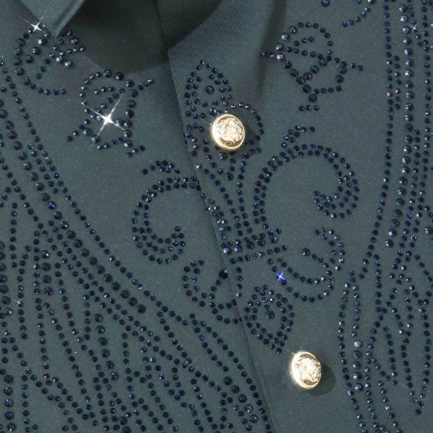 Close-up of green rhinestone wing shirt with decorative gold-tone buttons